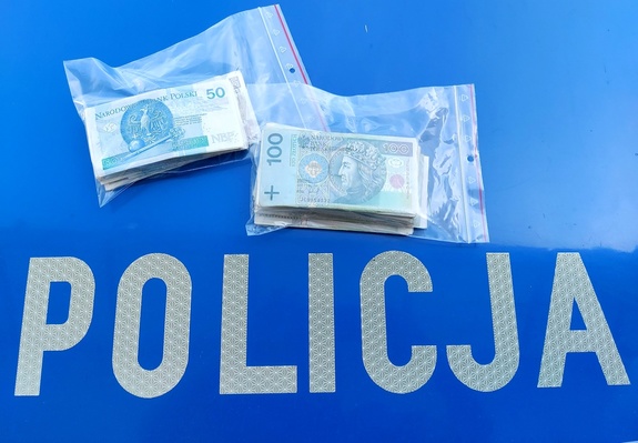 Pieniądze w woreczkach foliowych na masce radiowozu oraz napis policja.