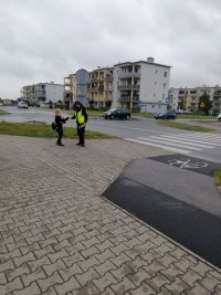 policjantka pod szkolą, rozmawia z uczniami którzy przechodza przez przejscie dla pieszych, wszystko podczas działań bezpieczna droga do szkoly