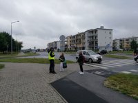 policjantka pod szkolą, rozmawia z uczniami którzy przechodza przez przejscie dla pieszych, wszystko podczas działań bezpieczna droga do szkoly