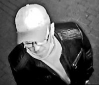 Fotografia z zapisu monitoringu, przedstawia sprawcę włamań do mieszkań w Bełchatowie. Mężczyzna ubrany na ciemno. Na głowie czarna czapka z daszkiem. Mężczyzna w okularach korekcyjnych, maseczka pod brodą
