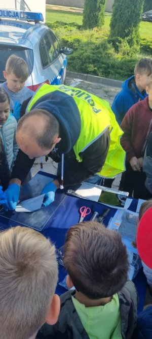 policjant pokazuje dzieciom jak zabezpiecza się ślady