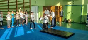 trenerzy aikido ćwiczący razem z dziećmi i policjantem