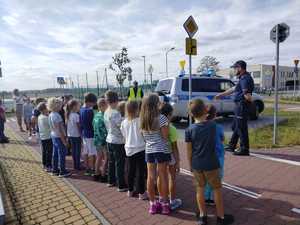 policjanci uczą dzieci bezpiecznych zachowań na przejściu dla pieszych.