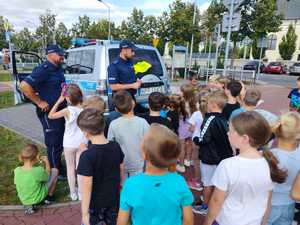 policjanci uczą dzieci zasad bezpiecznych zachowań w drodze do szkoły.