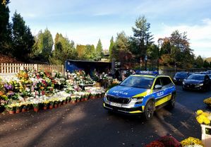 radiowóz policyjny w okolicy cmentarza, policjanci patrolują pobliski teren dbając o bezpieczeństwo osób, które przyjeżdżają na groby swych bliskich.