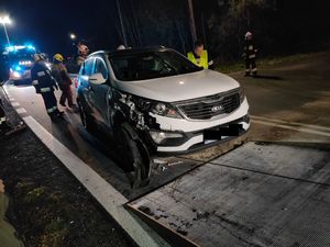 miejsce zdarzenia drogowego. na zdjęciu rozbity samochód osobowy, za nim dalej na miejscu widoczne służby ratunkowe.
