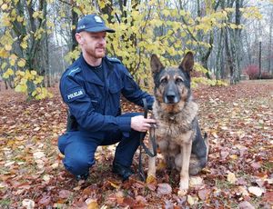 policjant z psem służbowym ćwiczą w terenie.