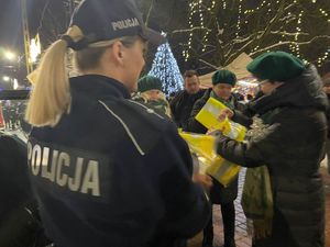 na świątecznym jarmarku policjantka rozdaje kamizelki odblaskowe.
