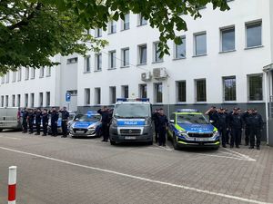 policjanci oddają cześć, stoją przy trzech radiowozach,w tle budynek komendy bełchatowskiej policji.