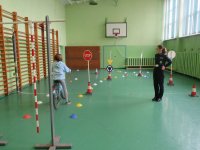 egzamin na kartę rowerową, dziewczynka w obecności policjantki jadąca na rowerze pokonuje tor przeszkód. egzamin miał miejsce w SzP nr 8 w Bełchatowie