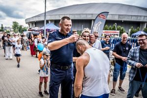 Komendant wręcza medal uczestnikowi biegu.