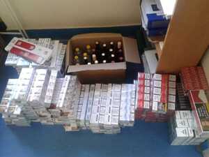 kontrabanda zabezpieczona przez policjantów, karton z butelkami alkoholu oraz paczki z papierosami