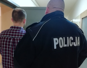 policjant prowadzi nietrzeźwego kierowcę sprawcę usiłowania kradzieży auta.