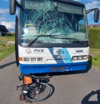 autobus pod którym częściowo leży rower