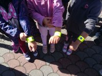 Dzieci pokazują założone na ręce opaski odblaskowe