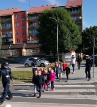 Dzieci w towarzystwie policjantki przechodzą przez przejście dla pieszych