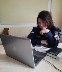 Policjantka siedzi przed laptopem i prowadzi zajęcia przez Internet