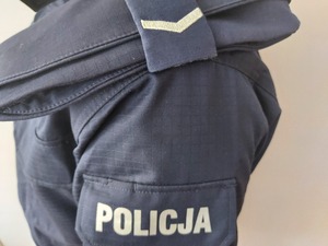 zdjęcie ramienia mężczyzny w umundurowaniu policyjnym. widoczny stopień sierżant oraz napis policja