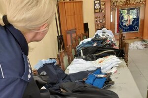 policjantka w pomieszczeniu służbowym podczas oględzin zabezpieczonej odzieży pochodzącej z przestępstwa.
