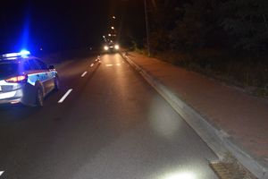 miejsce wypadku drogowego motocyklisty, zdjęcie zrobione nocą. droga, widoczny częściowo radiowóz policyjny