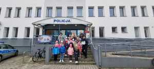 grupa przedszkolna z policjantką przed wejściem głównym do budynku komendy powiatowej w Bełchatowie