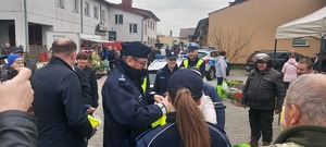 akcja rozdawania kamizelek odblaskowych na targowisku w Szczercowie. Policjanci i wojt gminy ubierają pieszych i rowerzystów w kamizelki