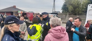 akcja rozdawania kamizelek odblaskowych na targowisku w Szczercowie. Policjanci i wójt gminy ubierają pieszych i rowerzystów w kamizelki