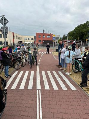 spotkanie z uczniami, policjanci egzaminują młodych rowerzystów w ramach praktycznego egzaminu na kartę rowerową. wszyscy stoją przy przejściu dla pieszych.