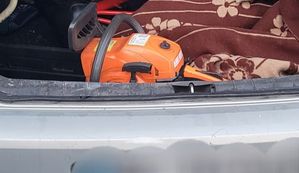Pomarańczowa piła do cięcia drzewa, leży w bagażniku auta