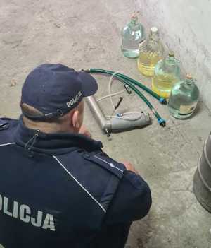 policjant w trakcie oględzin zabezpieczonego nielegalnego alkoholu.