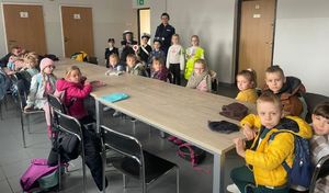policjantka z zespołu profilaktyki społecznej komendy policji w czasie spotkania z przedszkolakami, zdjęcie zrobione w pomieszczeniu komendy, dzieci siedzą przy stołach.