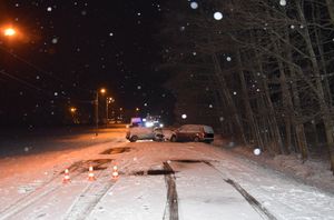 miejsce kolizji, dwa samochody osobowe które zderzyły się przodem, droga na której zalega śnieg. dalej pojazdy służb ratunkowych.