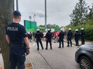 policjanci w czasie zabezpieczenia meczu, dalej widoczni kibice i stadion.