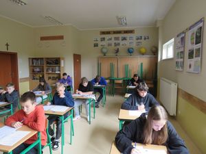 uczniowie w klasie przy ławkach rozwiązują test teoretyczny.