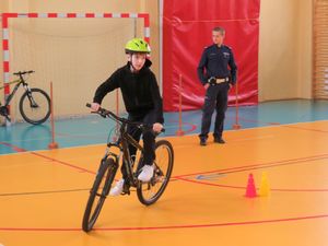 uczestnik turnieju pokonuje rowerowy tor przeszkód pod okiem policjanta.