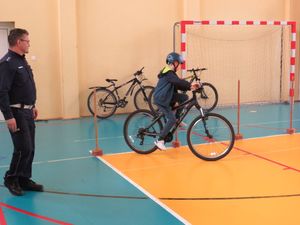 uczestnik turnieju pokonuje rowerowy tor przeszkód pod okiem policjanta.