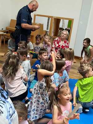 policjant z dziećmi w szkole prowadzi zajęcia o bezpieczeństwie w czasie wakacji.