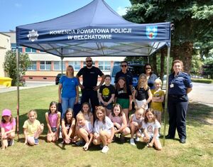 Pod policyjnym namiotem policjanci z dziećmi uczestniczącymi w wydarzeniu Bezpieczne Wakacje w Powiatowy Centru Sportu.