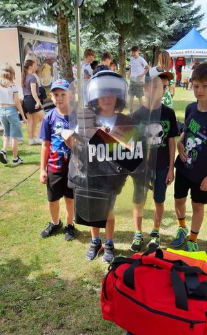 dzieci, chłopiec ma założony kask policyjny i trzyma tarczę policyjną.
