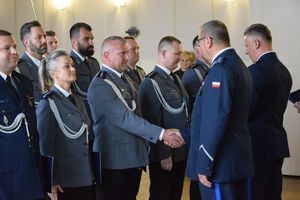 zdjęcie policjantów z uroczystości obchodów święta Policji w Bełchatowie. Policjanci odbierają awanse z rąk Komendanta Wojewódzkiego Policji w Lodzi.