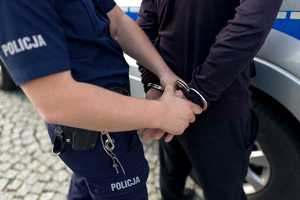 zdjęcie pokazuje jak policjant zakłada kajdanki na ręce mężczyzny. Policjant i zatrzymana osoba widoczna jest tylko w części ich rąk.