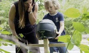 na zdjęciu kobieta z dzieckiem trzymającym kask, który zakłada na krzyż.