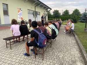 policjant na spotkaniu profilaktycznym z dziećmi wyjeżdżającymi na wakacje.