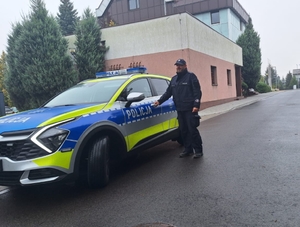 policjant stoi przy radiowozie.