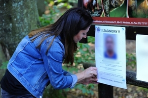 zdjęcie kobiety wieszającej plakat z napisem zaginiony.