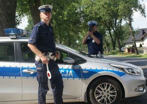 policjant stojący przy radiowozie.