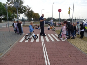 dzielnicowi na spotkaniu z dziećmi. uczą je bezpieczeństwa na przejściu dla pieszych.