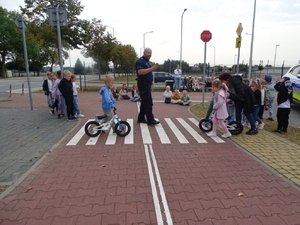 dzielnicowi na spotkaniu z dziećmi. uczą je bezpieczeństwa na przejściu dla pieszych.