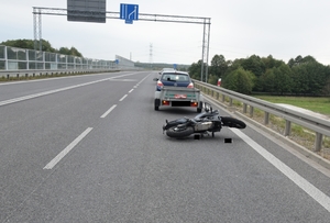 miejsce zdarzenia drogowego, na drodze leży motocykl przed nim stoi samochód z przyczepką.