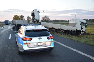 miejsce śmiertelnego wypadku drogowego,radiowóz policyjny na drodze, dalej pojazd ciężarowy uczestniczący w zdarzeniu.